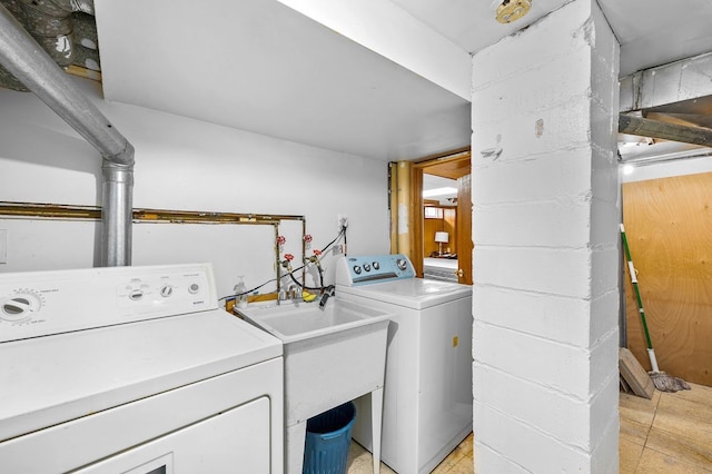 clothes washing area with washer and clothes dryer, laundry area, and a sink