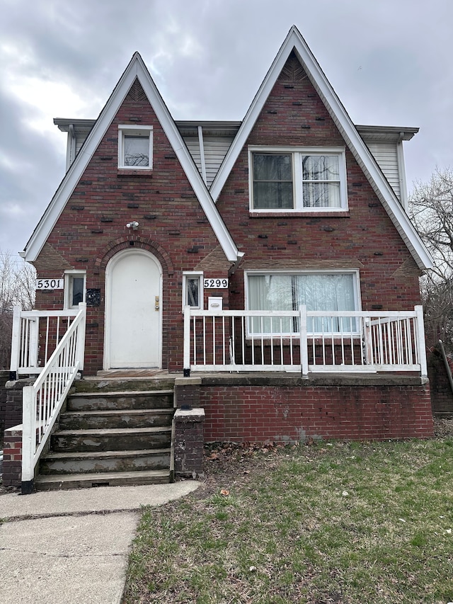 tudor home with covered porch and brick siding