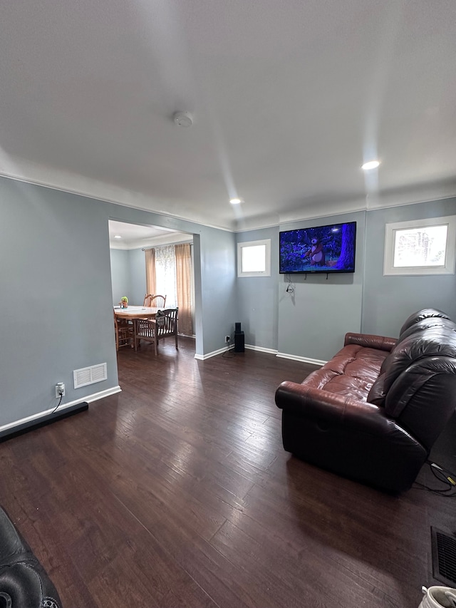 living area with baseboards, visible vents, and wood finished floors