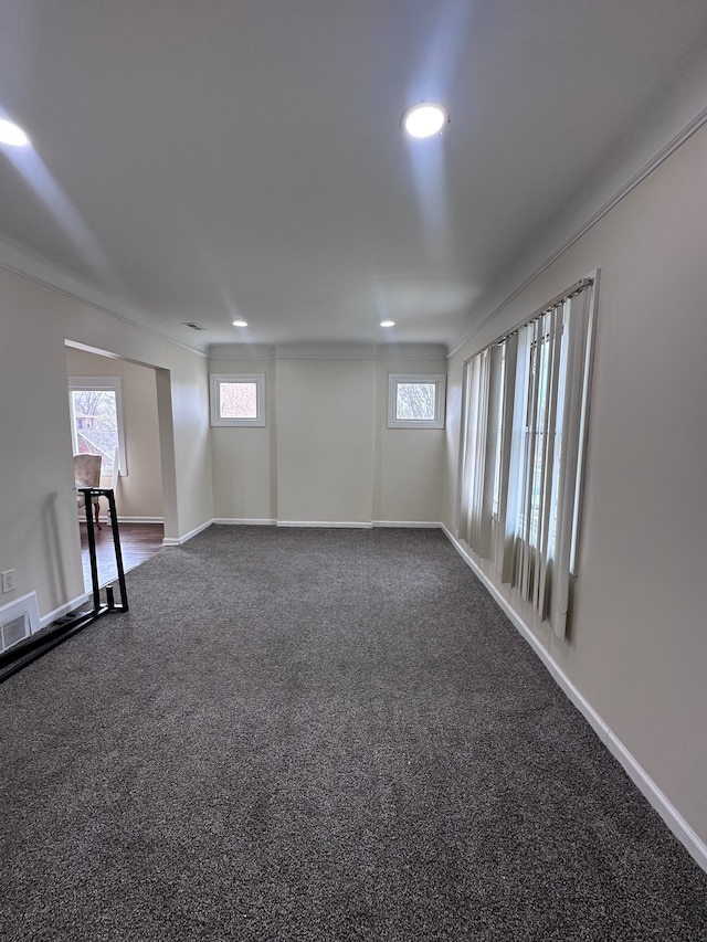spare room featuring baseboards, visible vents, dark carpet, and a healthy amount of sunlight