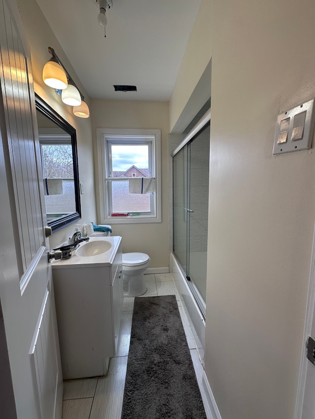 full bathroom with baseboards, toilet, bath / shower combo with glass door, and vanity