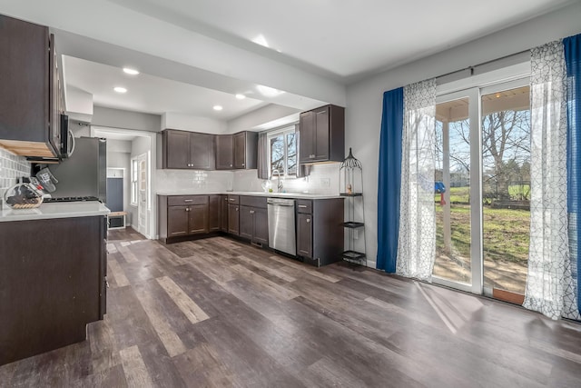 kitchen featuring light countertops, stainless steel appliances, decorative backsplash, dark wood-style floors, and dark brown cabinets