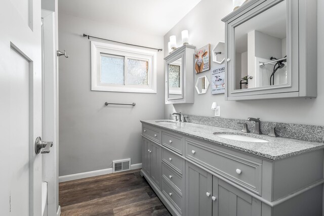 bathroom featuring baseboards, visible vents, wood finished floors, and a sink