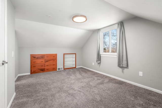 additional living space with carpet flooring, baseboards, lofted ceiling, and visible vents