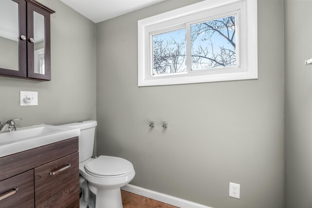 bathroom featuring baseboards, toilet, and vanity