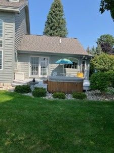rear view of house featuring a lawn and a hot tub