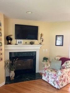 living area featuring baseboards, wood finished floors, and a glass covered fireplace