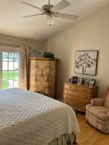 bedroom with ceiling fan, light wood-style flooring, and lofted ceiling