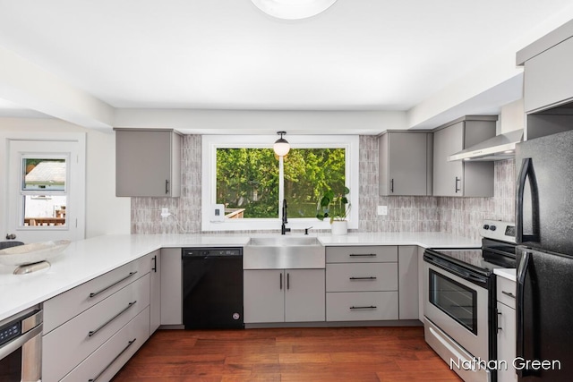 kitchen featuring gray cabinets, light countertops, a sink, black appliances, and dark wood-type flooring