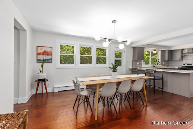 dining space featuring a notable chandelier, baseboard heating, baseboards, and dark wood finished floors