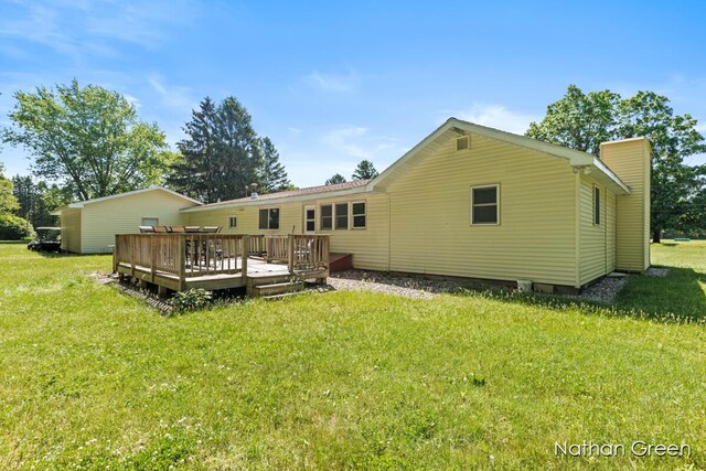 back of property with a chimney, a deck, and a yard