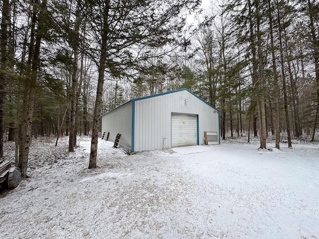 snow covered garage featuring driveway and a garage