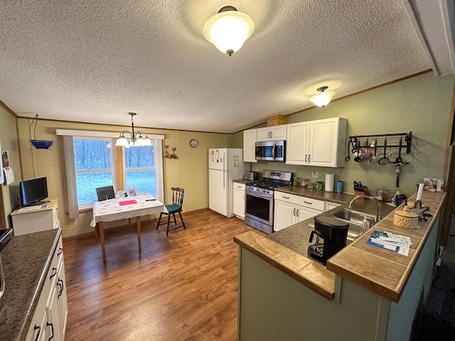 kitchen featuring wood finished floors, appliances with stainless steel finishes, lofted ceiling, and crown molding