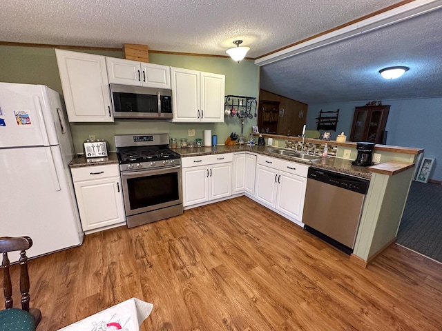 kitchen with light wood-style flooring, a sink, stainless steel appliances, and a peninsula
