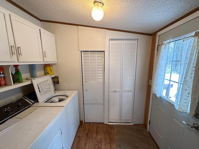 clothes washing area with crown molding, separate washer and dryer, wood finished floors, plenty of natural light, and cabinet space