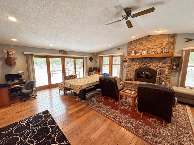 living room with hardwood / wood-style floors, lofted ceiling, ceiling fan, and a wealth of natural light