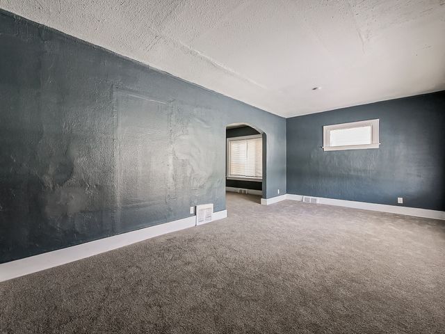 14011 Roselawn St, Detroit, MI 48238 - carpeted empty room with arched walkways, visible vents, and baseboards