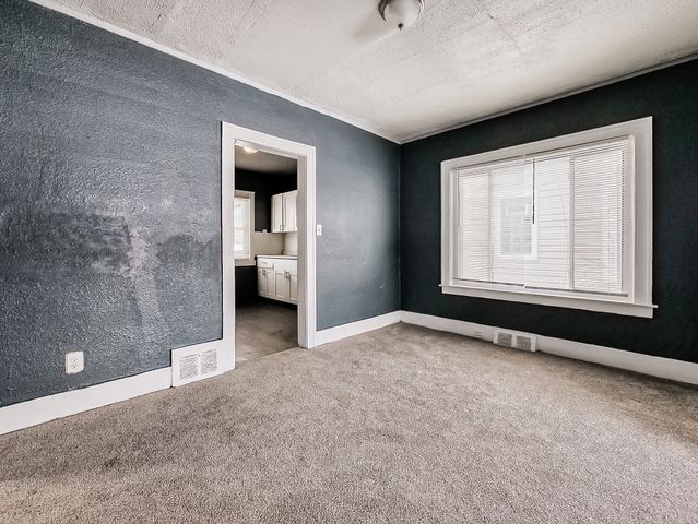 14011 Roselawn St, Detroit, MI 48238 - unfurnished bedroom with a textured ceiling, carpet flooring, baseboards, and visible vents