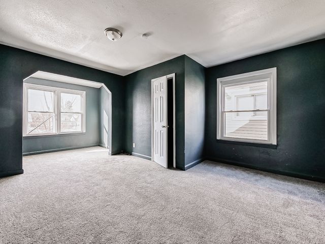 14011 Roselawn St, Detroit, MI 48238 - unfurnished bedroom with a textured ceiling, baseboards, and carpet floors