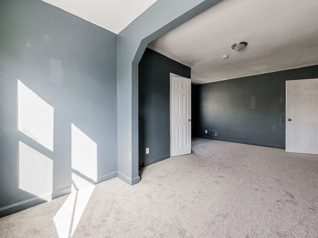 14011 Roselawn St, Detroit, MI 48238 - spare room featuring arched walkways, carpet flooring, and baseboards