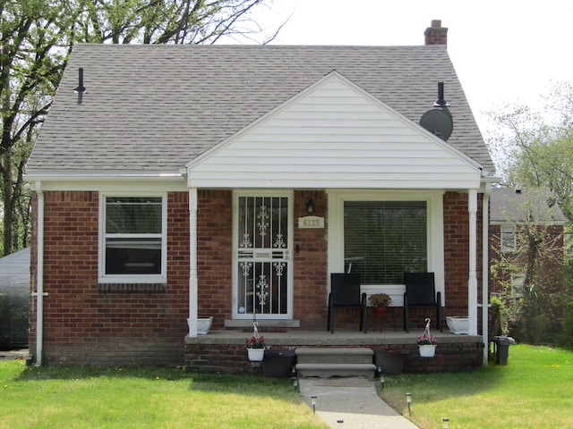 6125 Guilford St, Detroit, MI 48224 - view of front of home with a porch, brick siding, a chimney, roof with shingles, and a front lawn