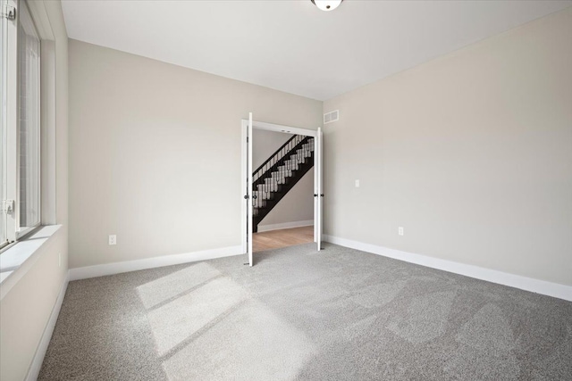 24599 Brookshire Dr, Macomb, MI 48042 - carpeted empty room featuring baseboards, stairs, and visible vents