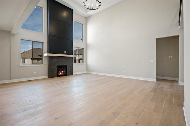 24599 Brookshire Dr, Macomb, MI 48042 - unfurnished living room featuring a high ceiling, a fireplace, light wood-style flooring, and a chandelier