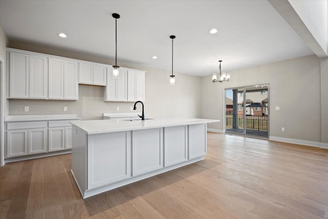 24599 Brookshire Dr, Macomb, MI 48042 - kitchen with baseboards, a sink, light wood finished floors, and an inviting chandelier