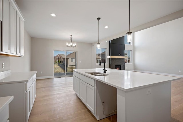 24599 Brookshire Dr, Macomb, MI 48042 - kitchen featuring open floor plan, a lit fireplace, a sink, and light wood-type flooring