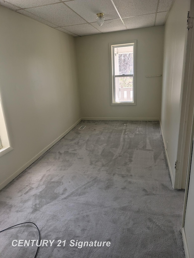 spare room with baseboards, carpet flooring, and a drop ceiling