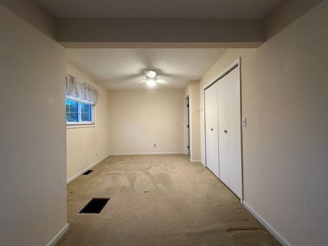 unfurnished bedroom featuring baseboards, visible vents, a closet, and carpet
