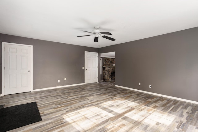 4725 Hickory Dr, Highland, MI 48356 - spare room featuring ceiling fan, wood finished floors, and a stone fireplace