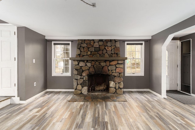 4725 Hickory Dr, Highland, MI 48356 - unfurnished living room with wood finished floors, a fireplace, and arched walkways