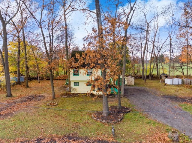 4725 Hickory Dr, Highland, MI 48356 - view of front facade with a storage unit, driveway, and a front lawn