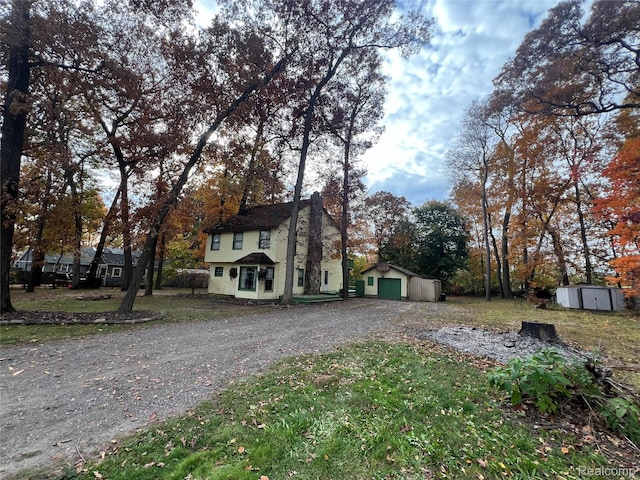 4725 Hickory Dr, Highland, MI 48356 - view of side of home with gravel driveway, a garage, and a storage shed