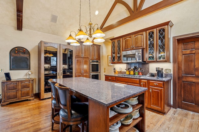 6242 131st St, Saugatuck, MI 49453 - kitchen with stainless steel appliances, a kitchen island, lofted ceiling, open shelves, and light wood-type flooring