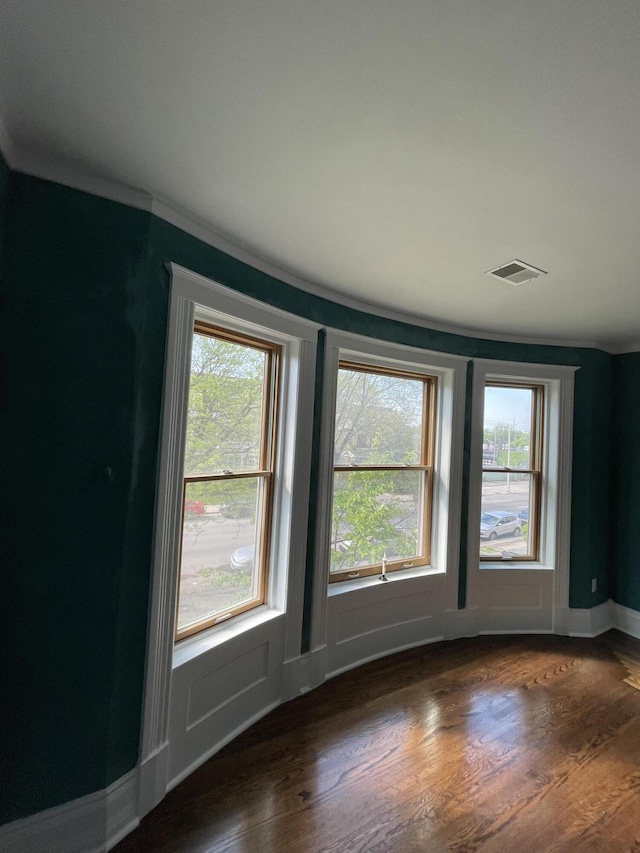 empty room with baseboards, visible vents, and wood finished floors