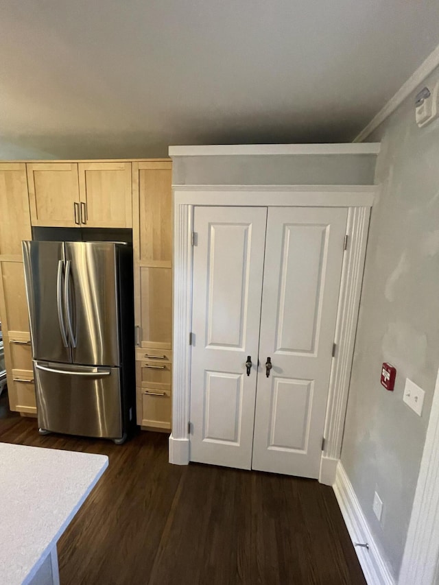 kitchen featuring light countertops, baseboards, dark wood-type flooring, light brown cabinetry, and freestanding refrigerator