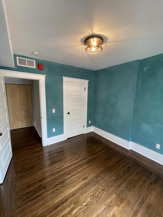spare room with baseboards, visible vents, and dark wood finished floors