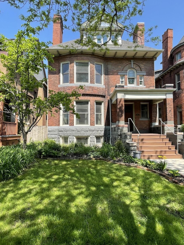 view of front of home with covered porch, brick siding, a front yard, and a chimney