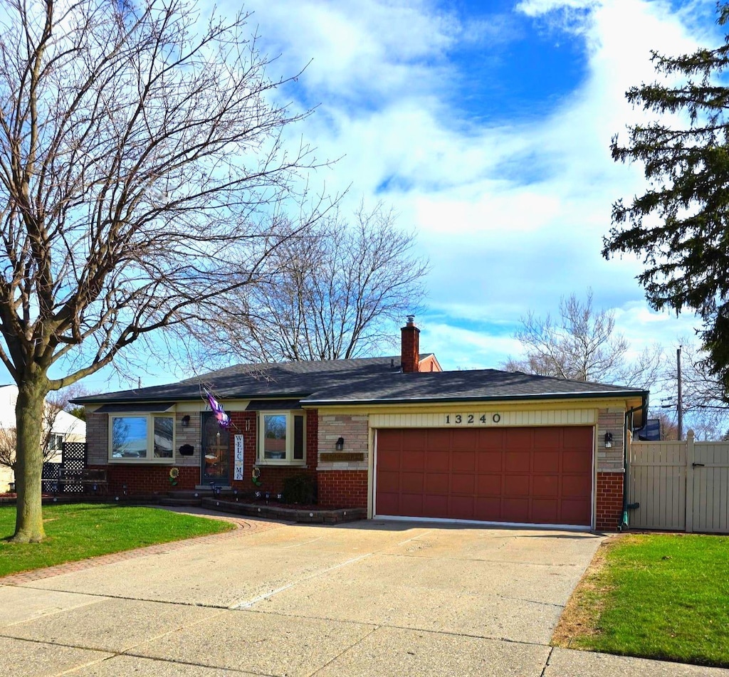 ranch-style home featuring driveway, fence, brick siding, an attached garage, and a front yard