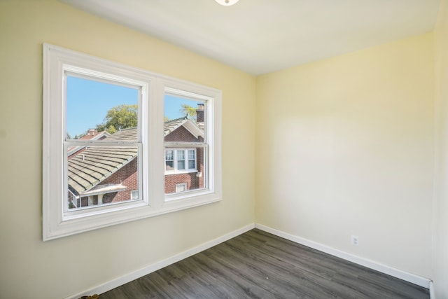 spare room with baseboards and dark wood-style floors