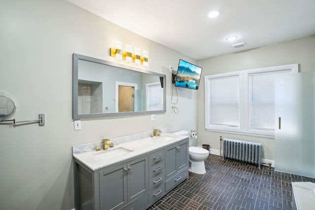 bathroom with radiator heating unit, toilet, double vanity, baseboards, and recessed lighting