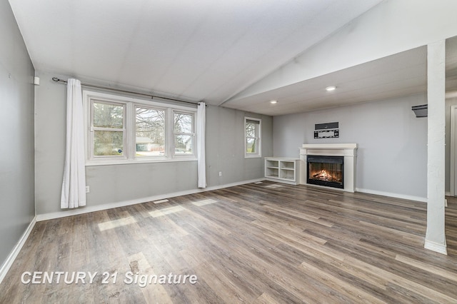 5024 Kencliff Dr, Saginaw, MI 48638 - unfurnished living room featuring a warm lit fireplace, baseboards, vaulted ceiling, and wood finished floors