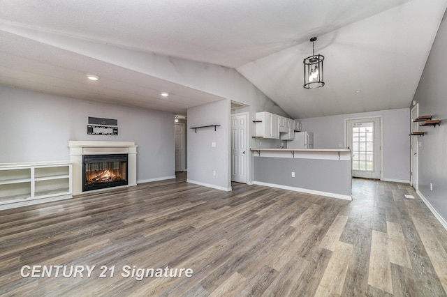 5024 Kencliff Dr, Saginaw, MI 48638 - unfurnished living room featuring baseboards, vaulted ceiling, wood finished floors, and a glass covered fireplace