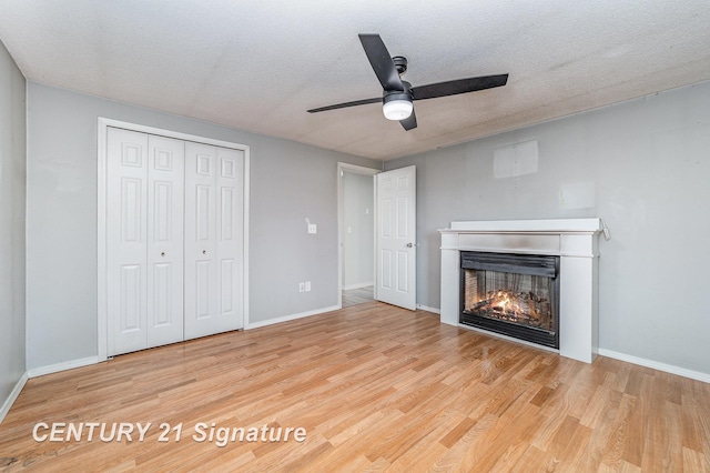5024 Kencliff Dr, Saginaw, MI 48638 - unfurnished living room with a lit fireplace, a textured ceiling, wood finished floors, and a ceiling fan