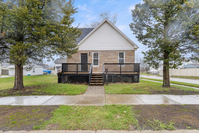 view of front of home with stone siding, a front yard, and a wooden deck