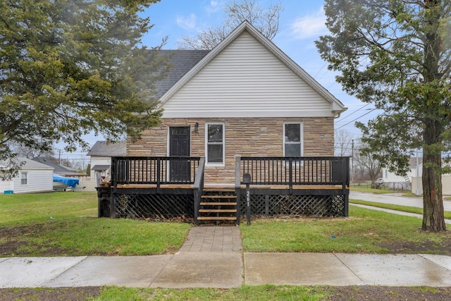 view of front of home featuring stone siding, a wooden deck, and a front lawn