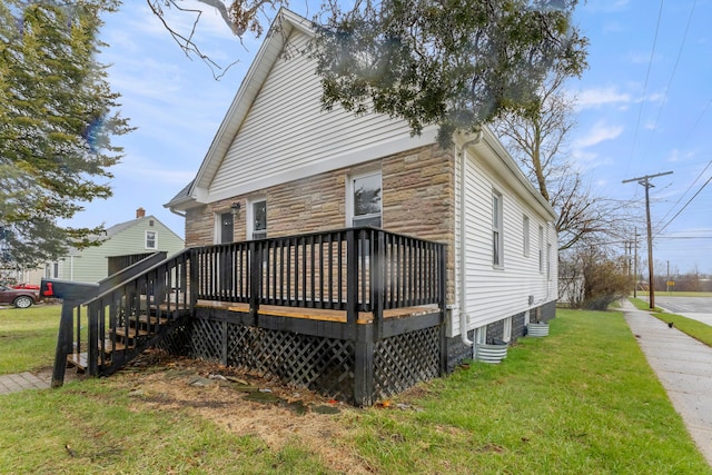 back of property featuring stone siding, a wooden deck, and a yard