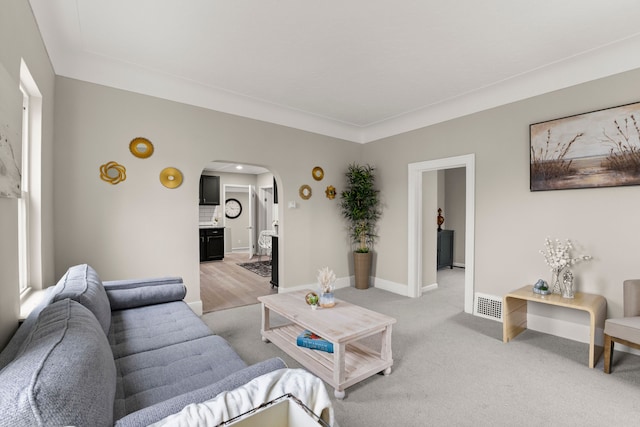 living room featuring arched walkways, baseboards, light colored carpet, and visible vents